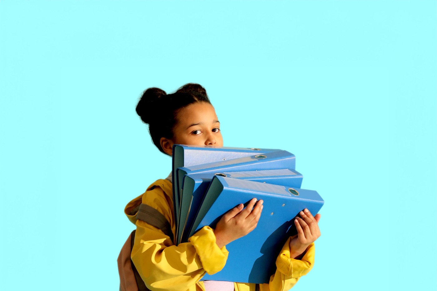 A girl carrying a tall stack of school binders